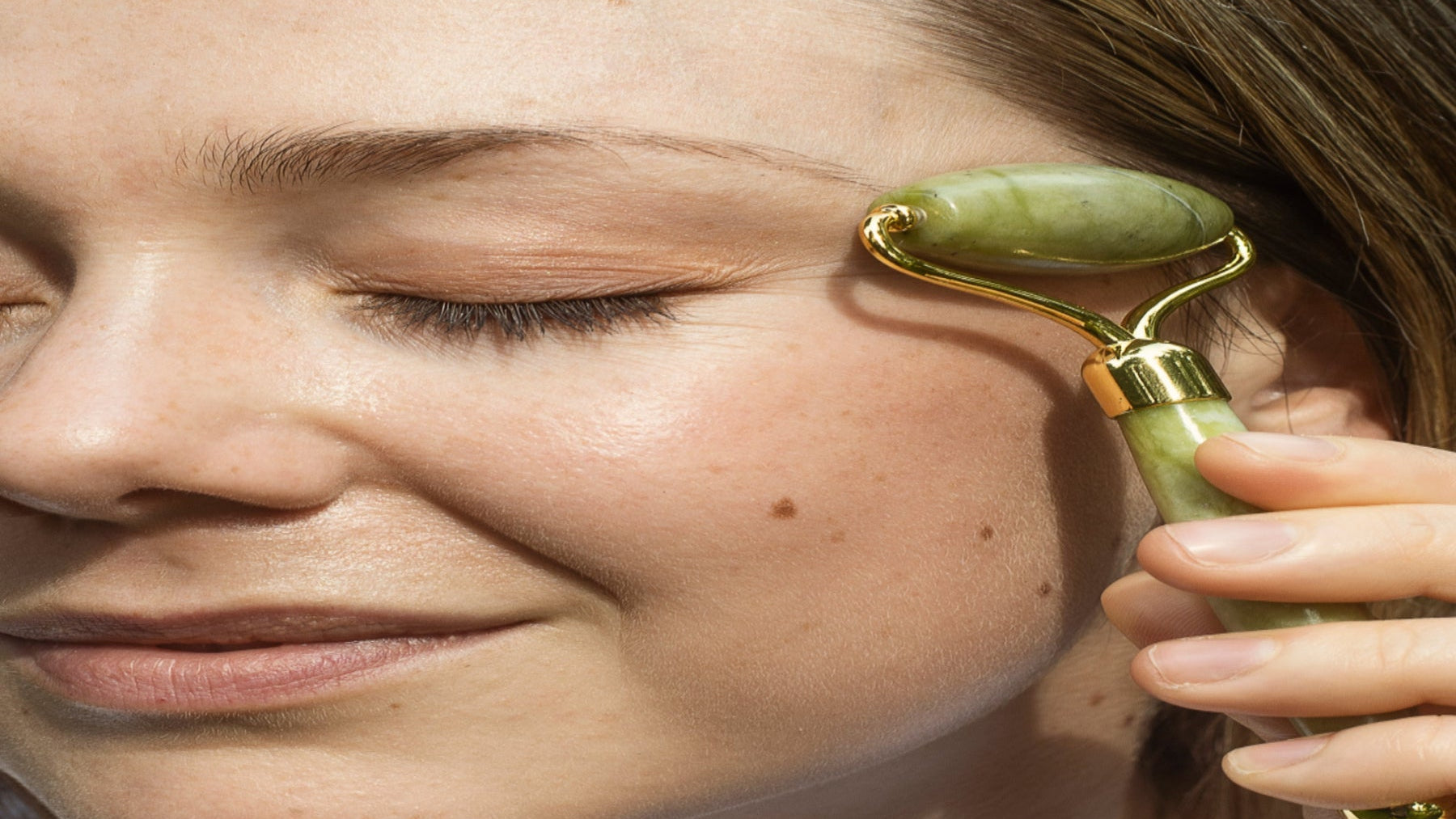 Woman using a jade roller on her face